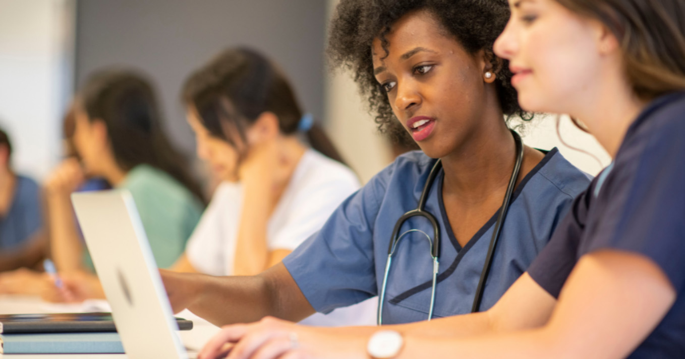 two professional nurses looking at a laptop