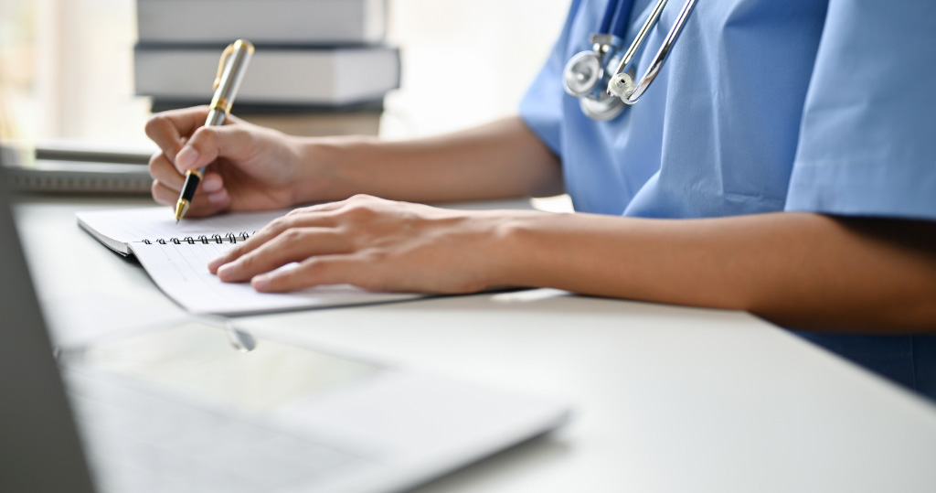 close up of nurse writing notes in a notebook